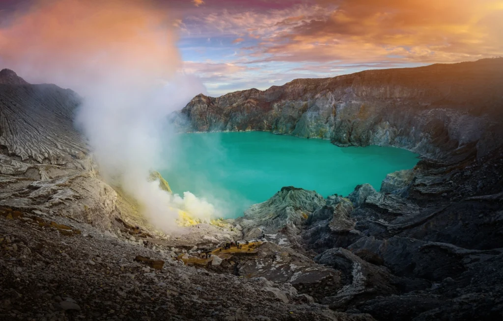 Gunung api Kawah Ijen dengan danau hijau dengan latar belakang langit biru pada pagi hari di Jawa Timur